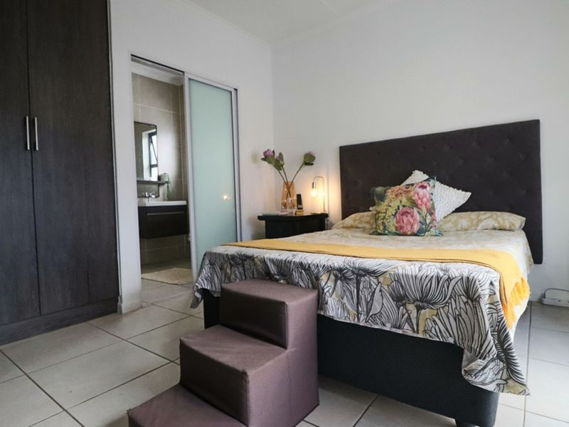 A well-maintained bedroom featuring tiled flooring, a large built-in wardrobe, and direct access to an en-suite bathroom through a sliding door.