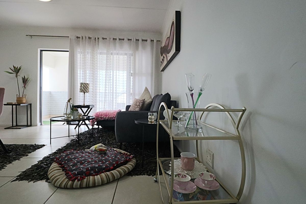 A well-lit living room featuring tiled flooring and a sliding glass door providing access to an outdoor balcony area.