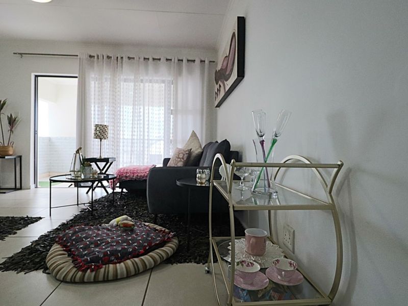 A well-lit living room featuring tiled flooring and a sliding glass door providing access to an outdoor balcony area.