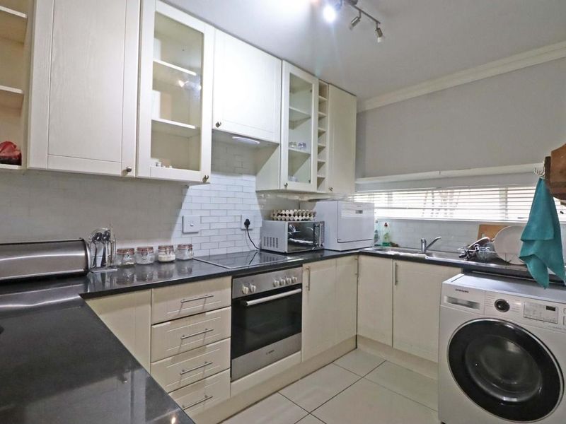 A functional kitchen featuring cream cabinetry, dark stone countertops, subway tile backsplash, and integrated appliances including an oven and cooktop.