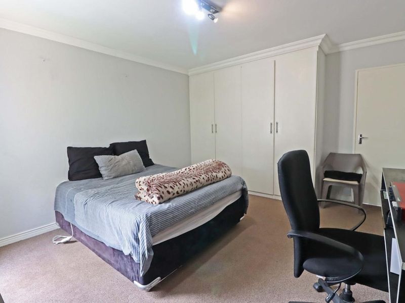 A bedroom featuring neutral walls, carpeted flooring, and ample built-in cupboard storage space.