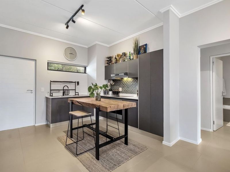 Modern kitchen featuring dark cabinetry, integrated appliances, tiled flooring, and a central breakfast island, with a clean, contemporary aesthetic.