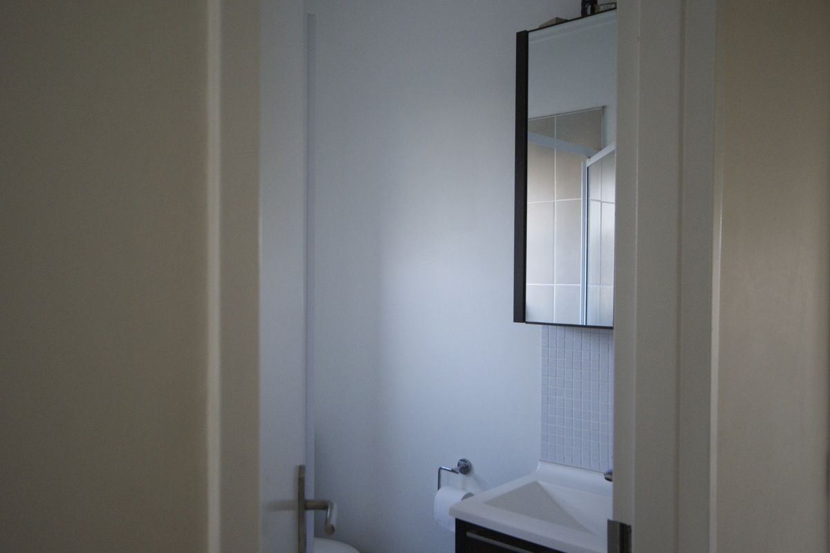 A compact bathroom featuring a modern vanity cabinet with an integrated sink, a wall-mounted mirror cabinet, and tiled splashback detailing.