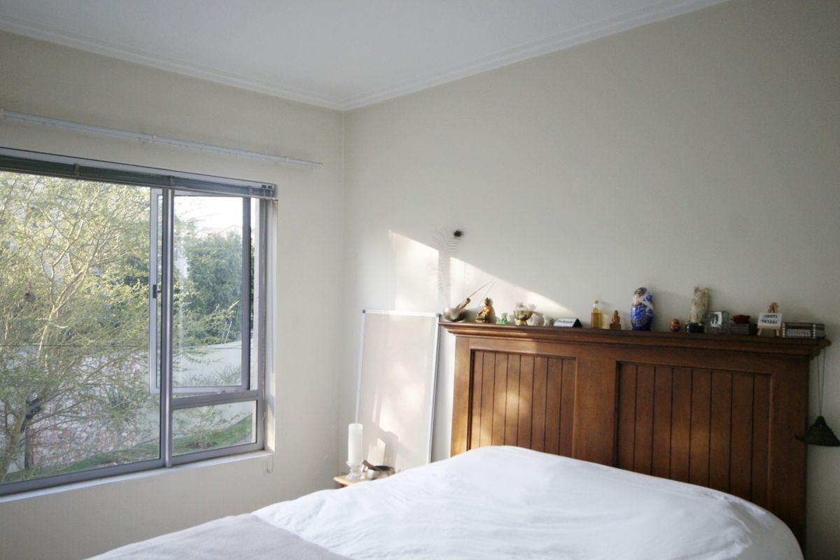 A bedroom featuring neutral walls, coving, and a large aluminium-framed window providing natural light and an exterior view.