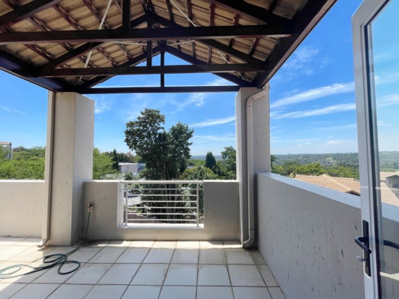 A covered balcony featuring tiled flooring, a timber roof structure, and a metal balustrade, offering elevated views of the surrounding area.