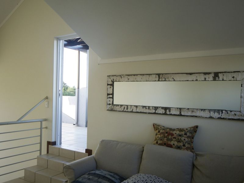 A living area featuring a vaulted ceiling, metal balustrade, and tiled steps leading to an outdoor balcony.