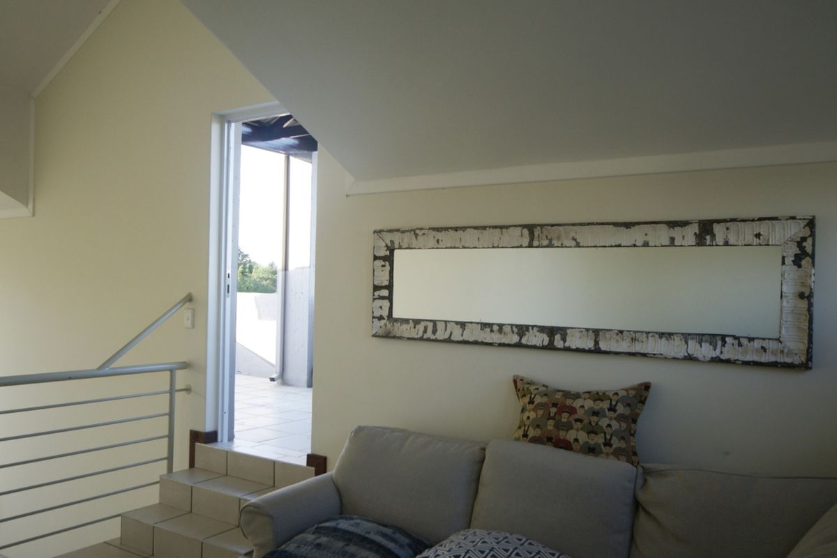 A living area featuring a vaulted ceiling, metal balustrade, and tiled steps leading to an outdoor balcony.