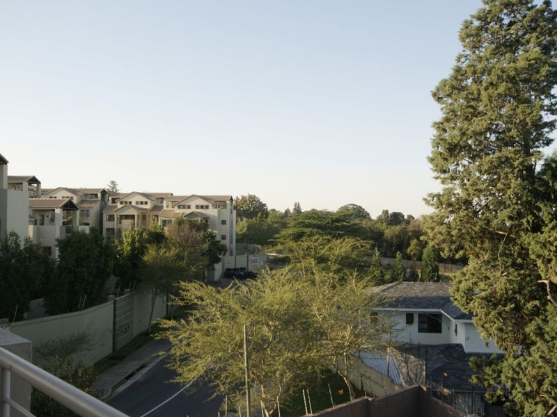 An elevated view overlooking the surrounding residential neighbourhood, featuring mature trees and neighbouring apartment complexes.