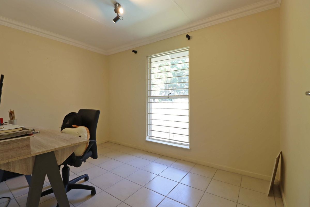 A functional bedroom featuring tiled flooring, security bars on the window, and ceiling-mounted spotlighting.