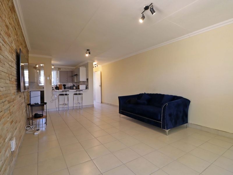 Open-plan living area featuring a stone accent wall, tiled flooring, and a compact kitchen with a breakfast counter.
