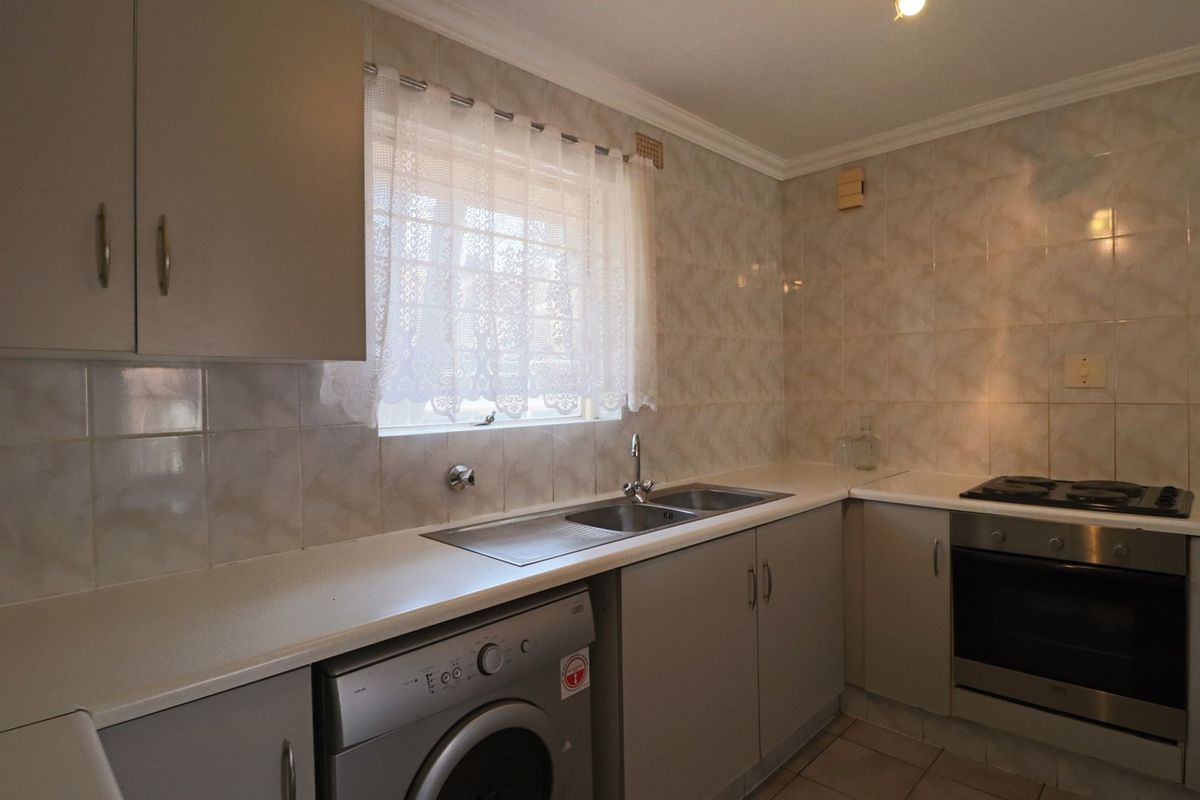 A functional kitchen featuring built-in cabinetry, a double sink, tiled splashbacks, and integrated oven and hob appliances.