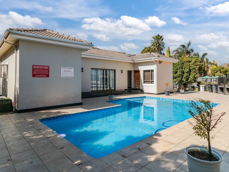 A well-maintained outdoor pool area featuring a tiled patio, swimming pool, and direct access to the building via sliding glass doors.