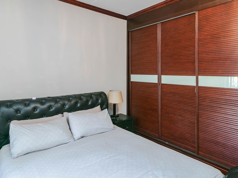 A well-maintained bedroom featuring a large, dark wood built-in sliding door wardrobe and classic crown molding details.