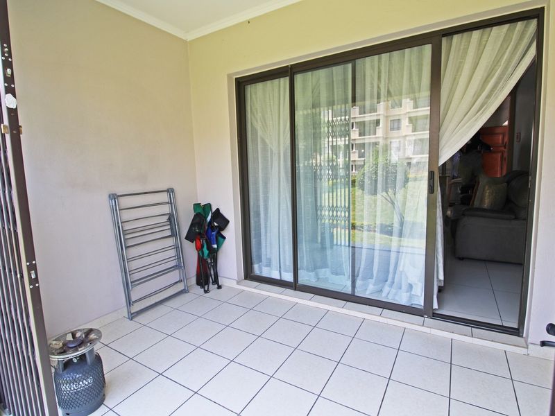 A covered balcony area featuring tiled flooring and a large sliding glass door providing access to the interior living space.