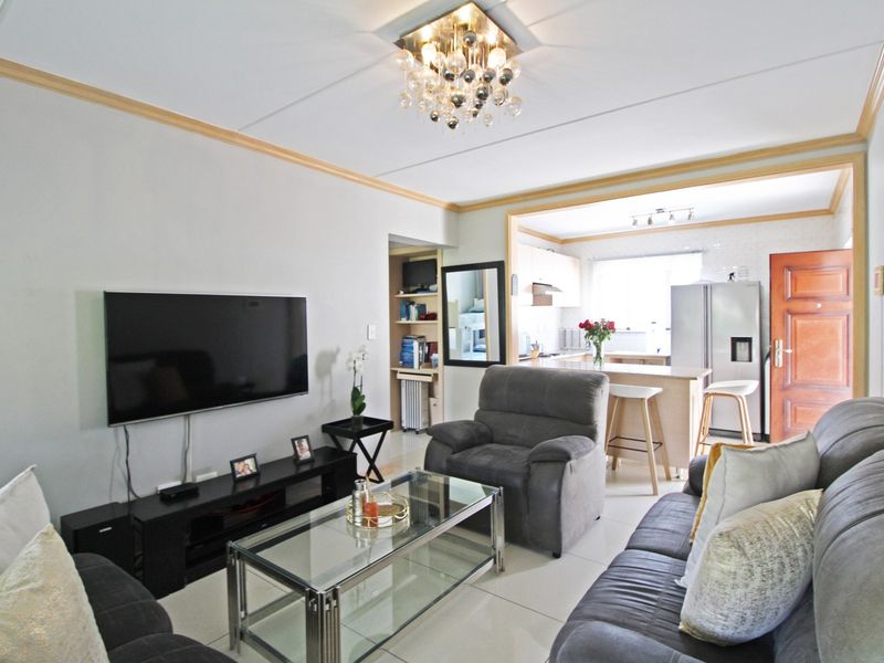 Open plan living area featuring tiled floors, a modern kitchen with island, and integrated shelving, creating a functional and connected living space.