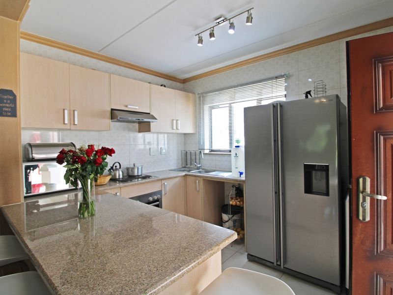 A functional kitchen featuring light wood cabinetry, granite countertops, a tiled backsplash, and integrated appliances, offering a clean and practical workspace.