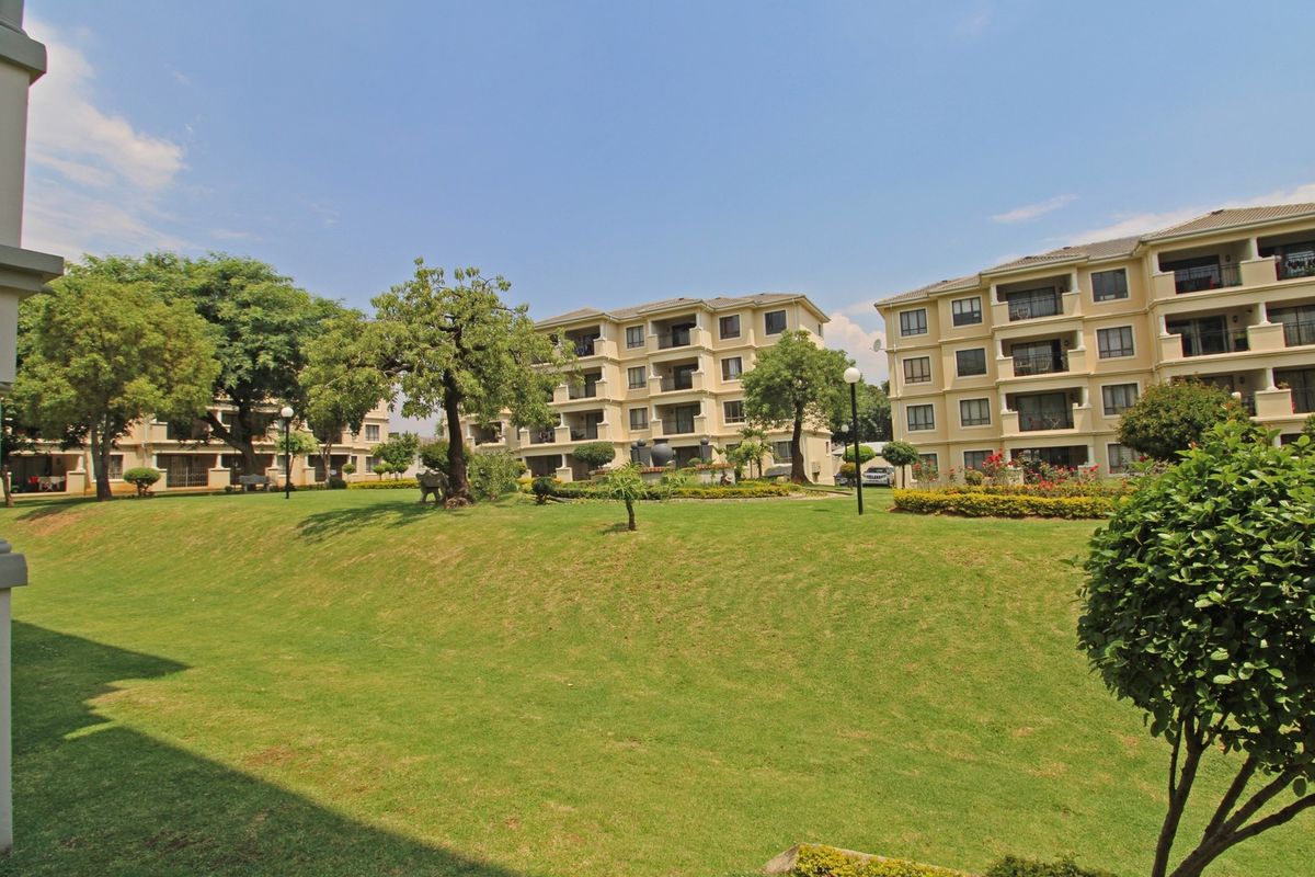 A view of the well-maintained communal garden area and landscaped grounds surrounding the multi-story apartment complex.