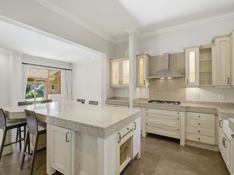 Spacious open-plan kitchen featuring a large central island, stone countertops, gas cooktop, and custom cabinetry, seamlessly flowing into the adjacent living area.