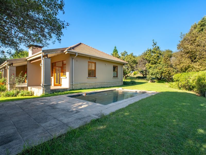 Rear view of the house featuring a swimming pool, paved patio area, and well-maintained garden surroundings.