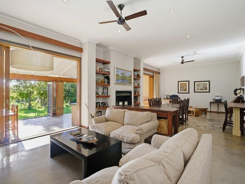 Spacious open-plan living and dining area featuring polished concrete floors, a built-in fireplace, and large sliding doors opening to a covered patio.