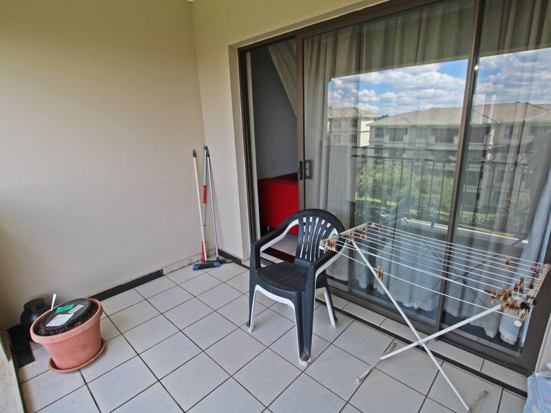 A functional balcony space featuring tiled flooring and a large sliding glass door providing access to the interior living area.