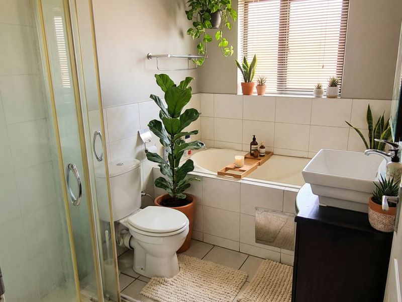 A functional bathroom featuring a shower enclosure, built-in bathtub, toilet, and a modern vessel sink set on a vanity cabinet.