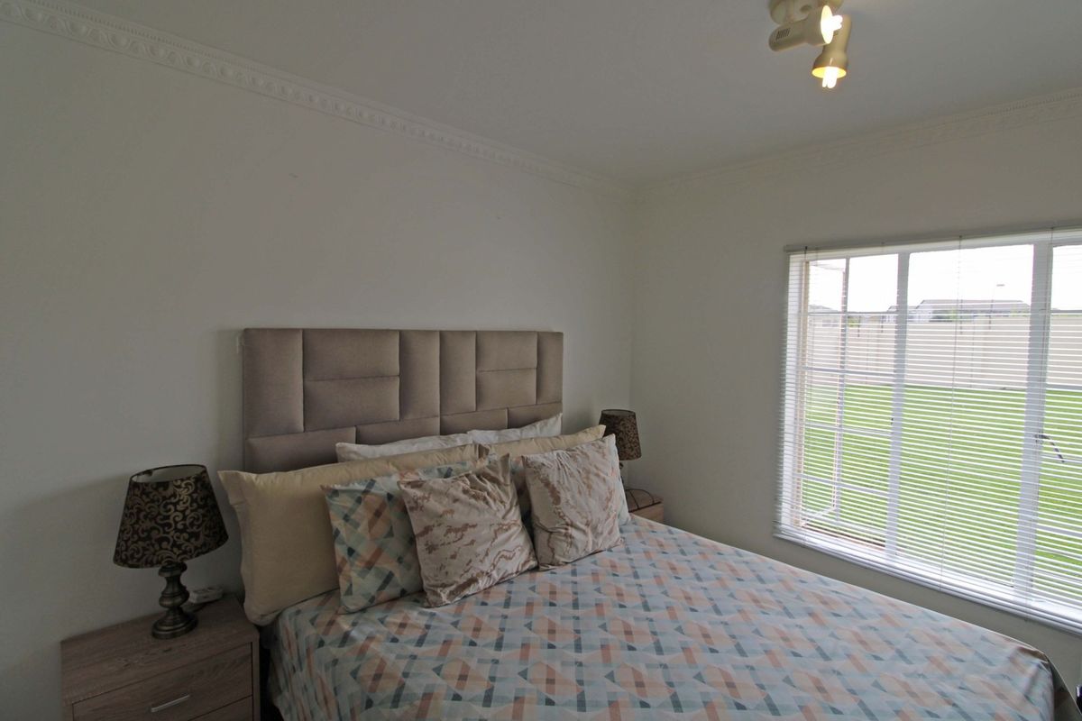 A well-maintained bedroom featuring crown molding, a window with fitted blinds, and a central ceiling light fixture.