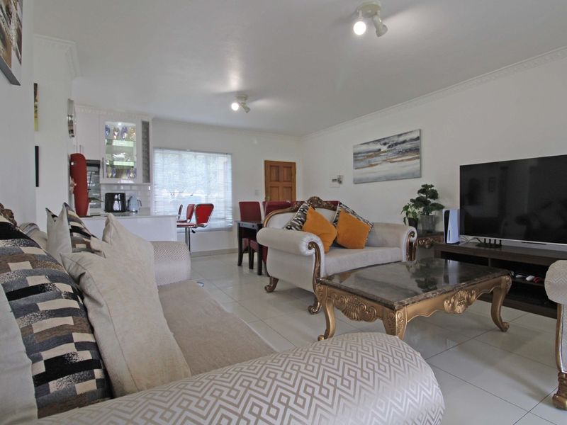 Open-plan living and kitchen area featuring tiled flooring, crown molding, and neutral wall finishes, providing a functional and connected living space.