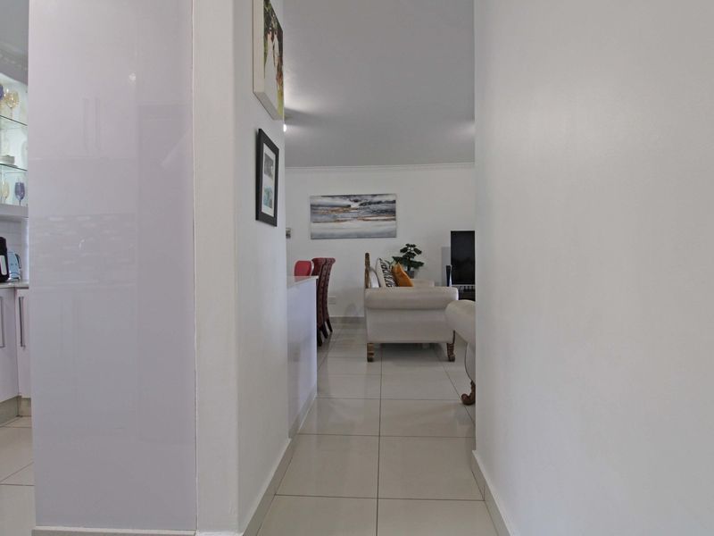 A view from a hallway into an open-plan living and kitchen area featuring tiled floors, built-in cabinetry, and an integrated oven.