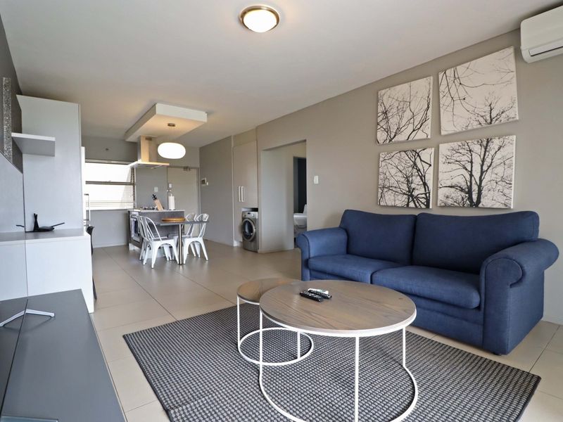 Spacious open-plan living and dining area featuring tiled floors, modern cabinetry, and a split-system air conditioner, creating a bright and functional living space.