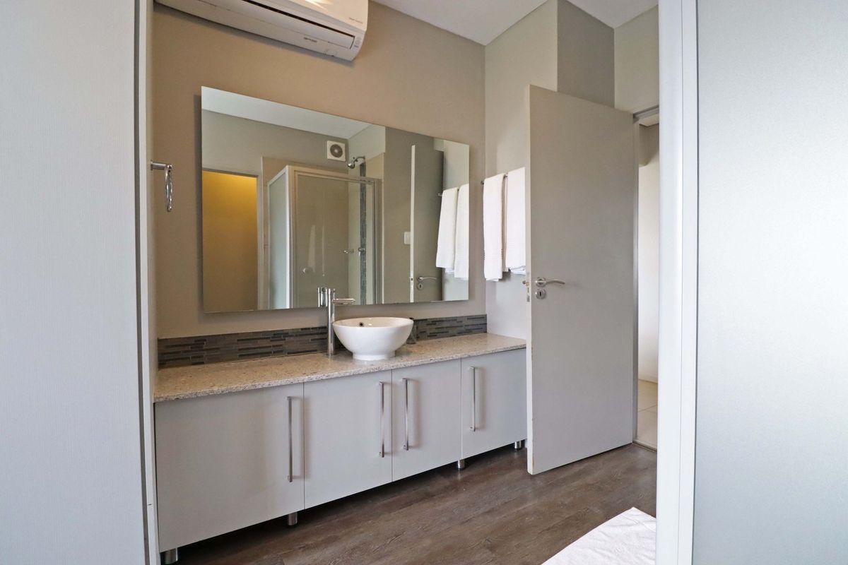Modern bathroom featuring a vanity with stone countertop, vessel sink, large wall mirror, and a separate shower enclosure.