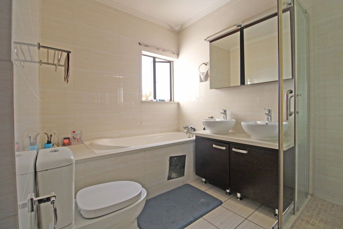 A functional bathroom featuring a dual vanity, built-in bathtub, separate shower enclosure, and tiled finishes throughout.