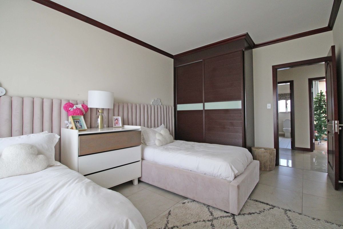 A well-maintained bedroom featuring tiled flooring, crown molding, and a large built-in wardrobe with sliding doors, providing ample storage space.