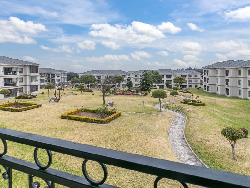 Elevated view overlooking a well-maintained communal garden area with paved pathways between apartment blocks.