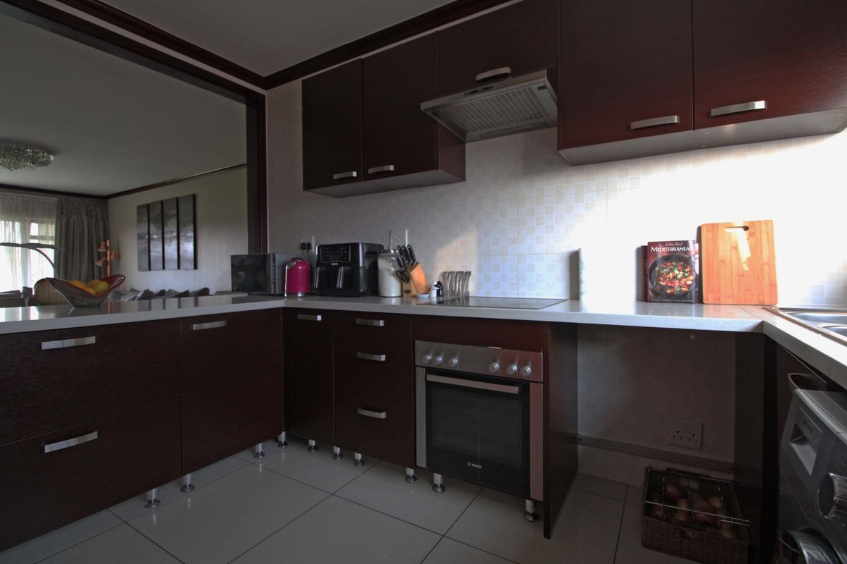 A functional kitchen featuring dark wood cabinetry, built-in oven, electric cooktop, and tiled backsplash, offering a practical layout for daily meal preparation.