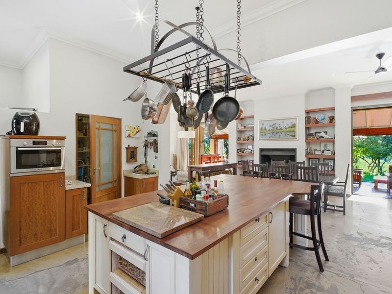 Spacious open-plan kitchen and living area featuring a large central island, built-in oven, fireplace, and direct access to an outdoor patio.