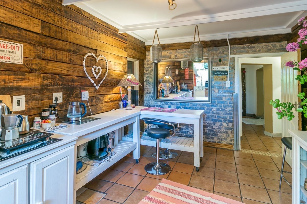 A rustic-style kitchen featuring timber wall cladding, exposed brickwork, and ceramic floor tiles with a built-in breakfast bar area.