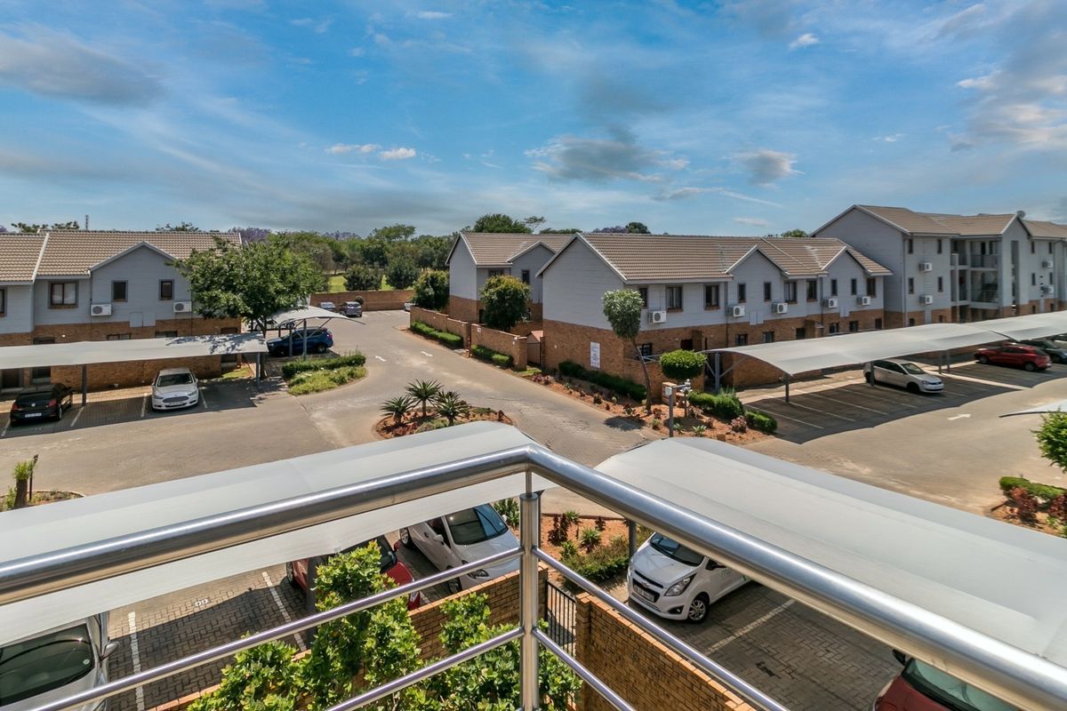 Elevated view overlooking the apartment complex grounds, featuring paved parking areas with covered carports and multi-story residential buildings.