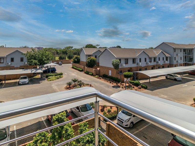 Elevated view overlooking the apartment complex grounds, featuring paved parking areas with covered carports and multi-story residential buildings.