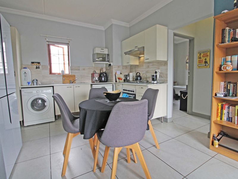 Open-plan kitchen featuring built-in cabinetry, tiled flooring, and integrated appliances, seamlessly connecting to the living area.