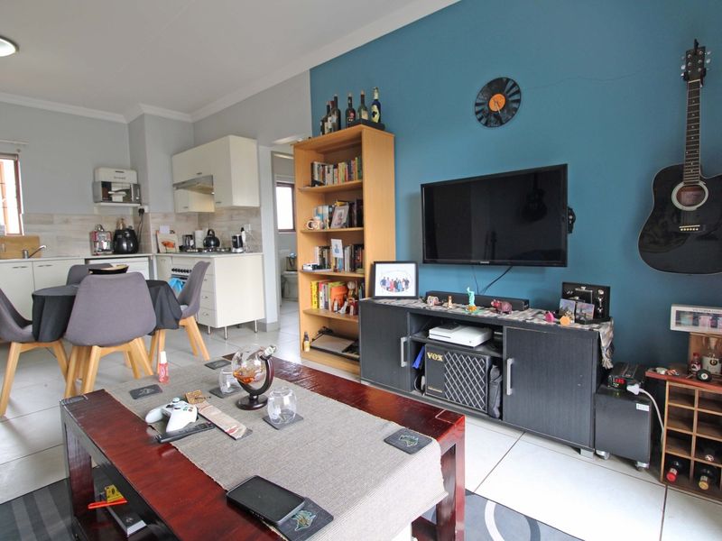 Open-plan living area featuring a combined kitchen with built-in cabinetry and a lounge space with tiled flooring throughout.