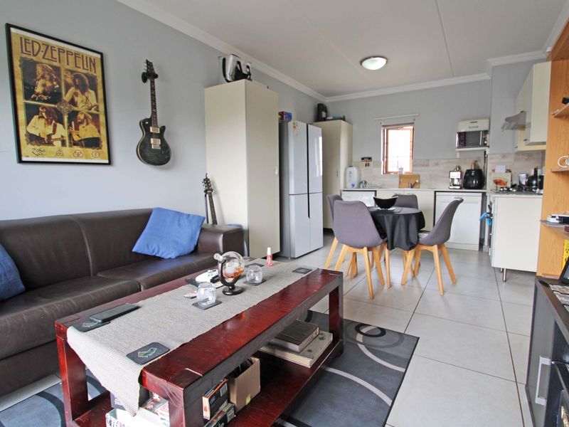 Open-plan living and kitchen area featuring tiled flooring and functional built-in cabinetry, offering a versatile space for dining and relaxation.