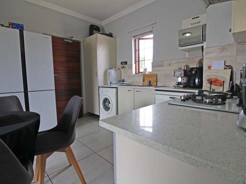 Functional kitchen featuring stone countertops, gas hob, built-in cabinetry, and integrated appliances with tiled flooring and neutral wall finishes.