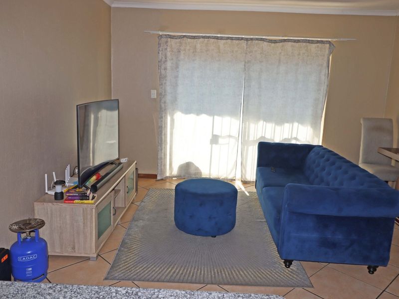 A living room area featuring tiled flooring and a sliding glass door providing natural light.