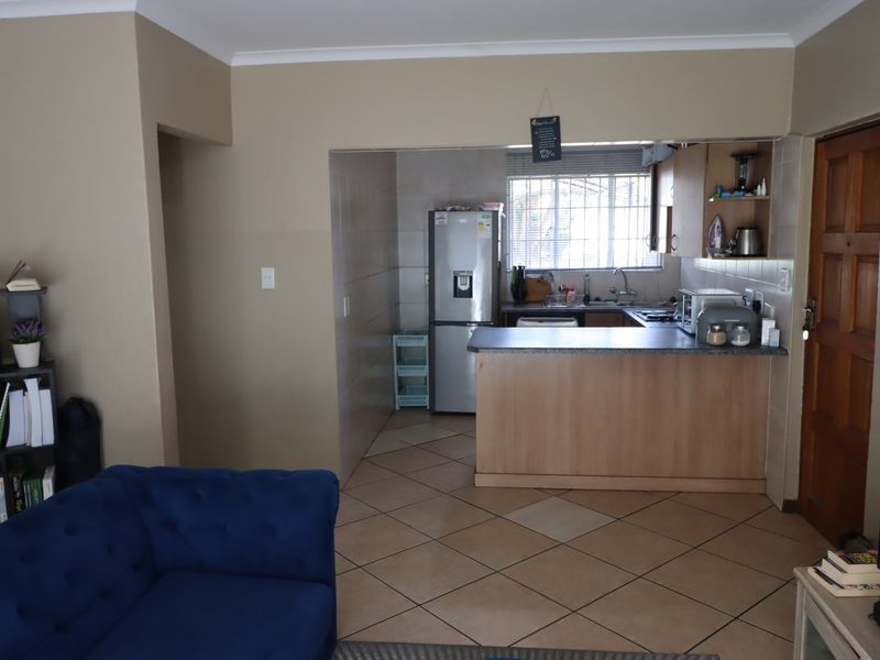 Open plan living area featuring a functional kitchen with laminate countertops, tiled flooring, and neutral wall tones, providing a practical layout for daily living.