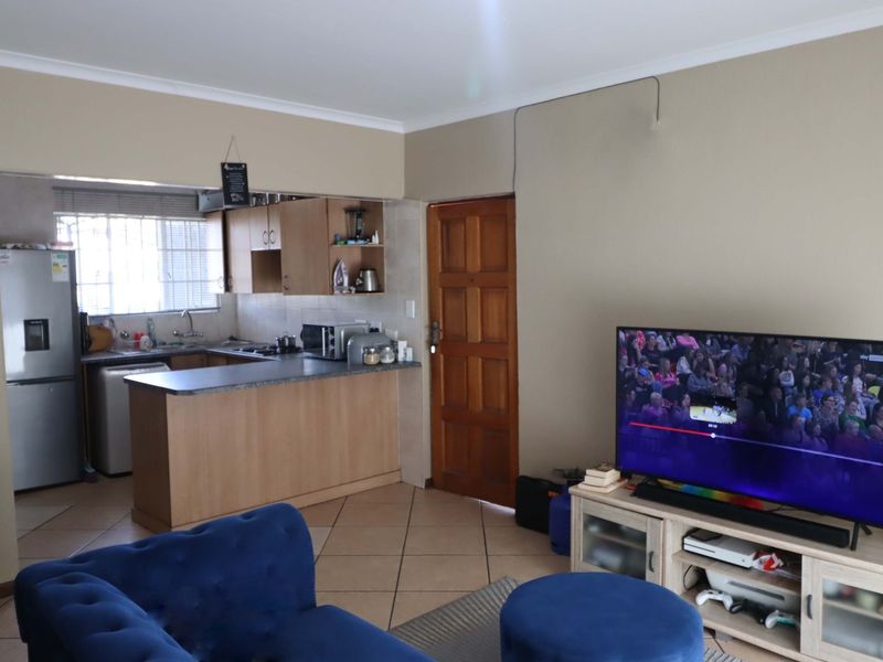 Open plan living area featuring a functional kitchen with laminate countertops and tiled flooring, seamlessly connected to the main living space.