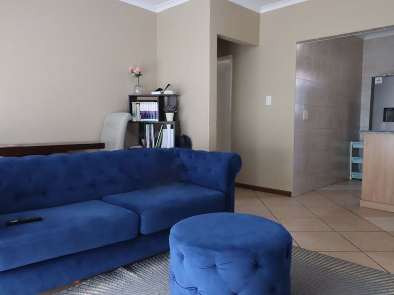 A living room area featuring tiled flooring and a pass-through opening into the kitchen space.