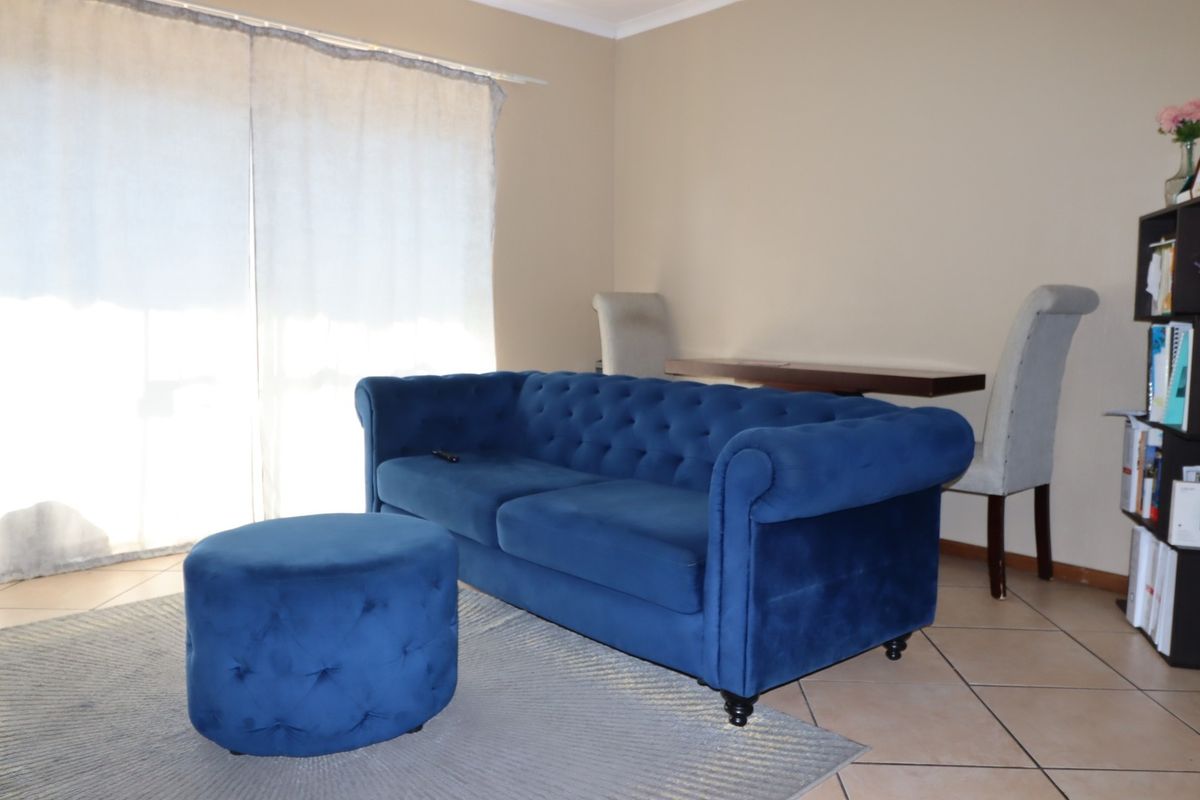 A living room area featuring tiled flooring and a large sliding glass door providing natural light.