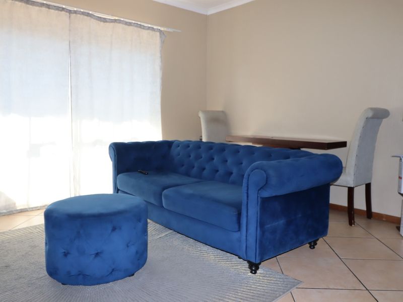 A living room area featuring tiled flooring and a large sliding glass door providing natural light.