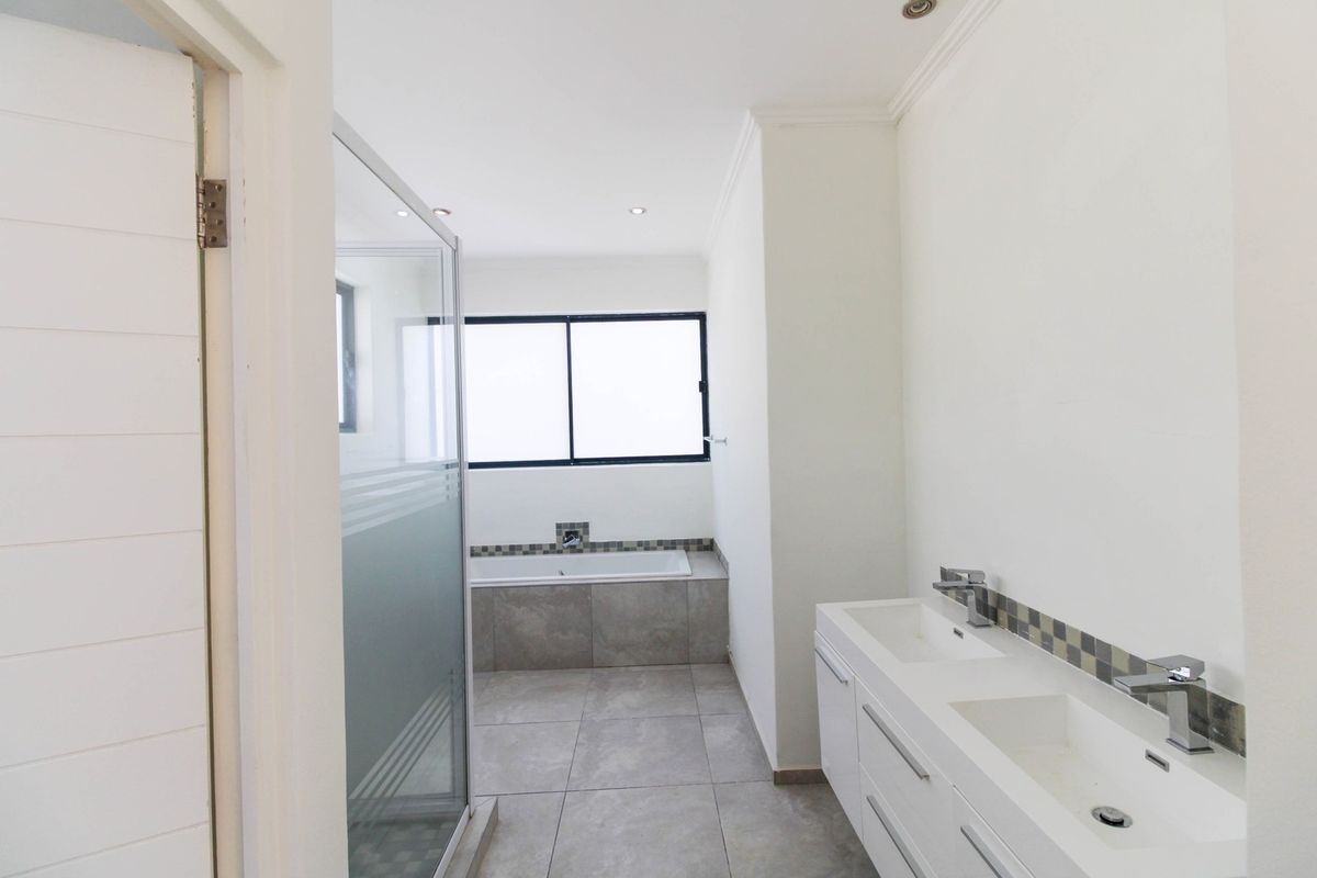 Modern bathroom featuring a double vanity, a built-in bathtub with mosaic tile accents, and a separate glass-enclosed shower.